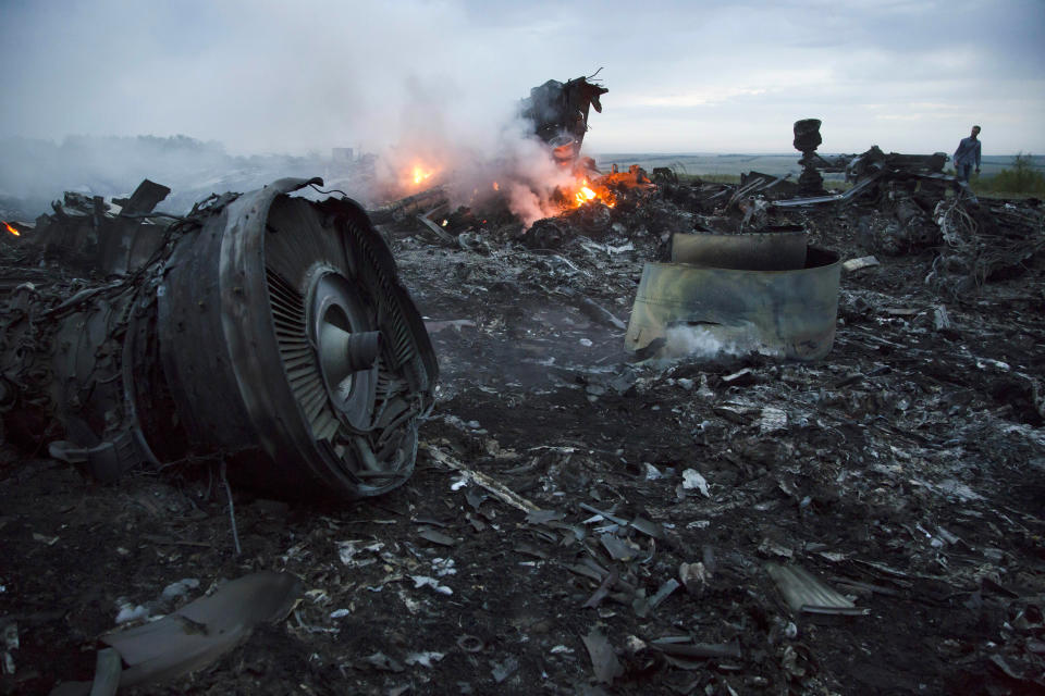 FILE - In this Thursday, July 17, 2014 file photo, a man walks amongst the debris at the crash site of a passenger plane near the village of Hrabove, Ukraine. An international team of investigators building a criminal case against those responsible in the downing of Malaysia Airlines Flight 17 is set to announce progress in the probe on Wednesday June 19, 2019, nearly five years after the plane was blown out of the sky above conflict-torn eastern Ukraine. (AP Photo/Dmitry Lovetsky, File)