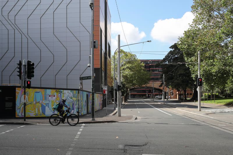 A man rides his bicycle by an almost empty street during a workday following the implementation of stricter social-distancing and self-isolation rules to limit the spread of the coronavirus disease (COVID-19) in Sydney