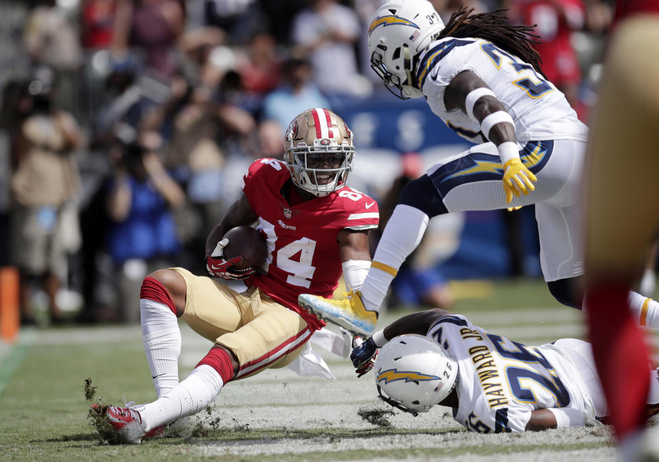 San Francisco 49ers wide receiver Kendrick Bourne, left, scores a touchdown after making a catch as Los Angeles Chargers defensive back Jahleel Addae, upper right, and defensive back Casey Hayward defend during the first half of an NFL football game, Sunday, Sept. 30, 2018, in Carson, Calif. (AP Photo/Jae Hong)