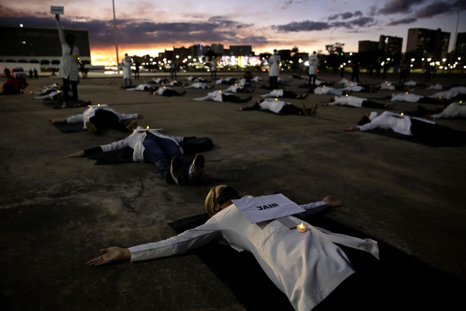 Nurses lay on the ground to represent colleagues who died in their fight against the new coronavirus pandemic, during a protest marking International Nurses Day, in Brasilia, Brazil, Tuesday, May 12, 2020. (AP Photo/Eraldo Peres)