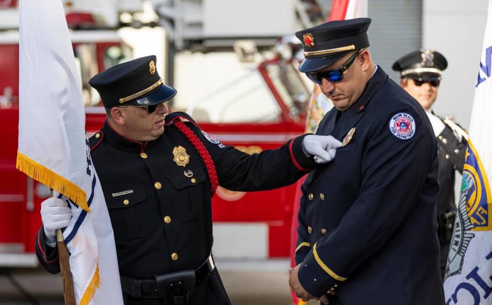 Miami Beach Firefighter Daniel Martinez, left, helps Lieutenant Christopher Merein with his uniform before the start of a September 11, 2001, remembrance ceremony at Fire Station 2 on Monday, Sept. 11, 2023, in Miami Beach, Fla.