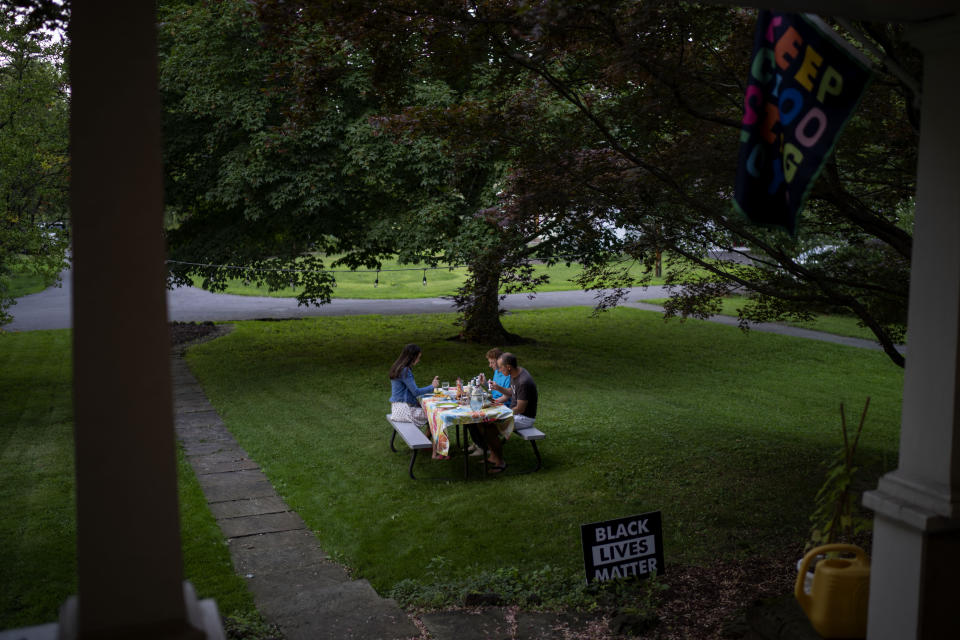 Rev. Stephen Cady, right, has dinner with this children, Ellie, 16, left, and Charlie, 14, outside their home in Rochester, N.Y., Monday, Aug. 21, 2023. For congregants of Asbury, the increasing frequency of shooting attacks on communal spaces has seeded a lingering sense that whether praying or sending their children to school, they need to be looking over their shoulders, Cady says. (AP Photo/David Goldman)