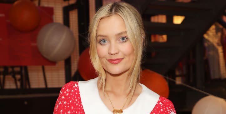 laura whitmore attends a press event wearing a red and white dress smiling at the camera