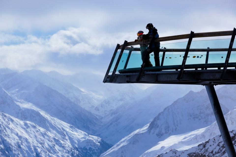 two skiers on an overlook of the snowy mountain