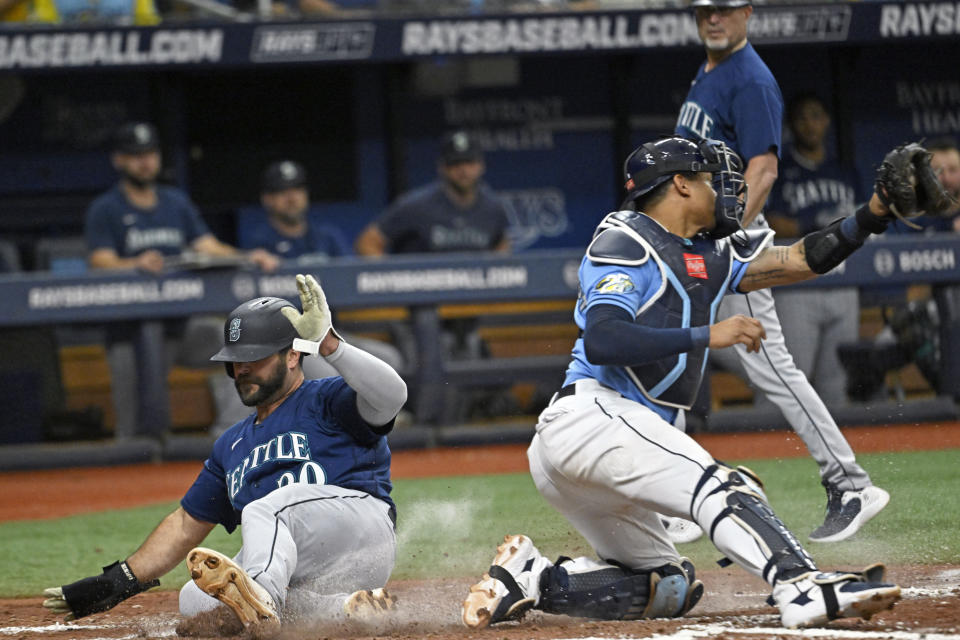 Seattle Mariners first baseman Mike Ford, left, beats the throw to Tampa Bay Rays catcher Christian Bethancourt to score on Sean Haggerty's RBI-single during the fourth inning of a baseball game, Sunday, Sept. 10, 2023, in St. Petersburg, Fla. (AP Photo/Steve Nesius)