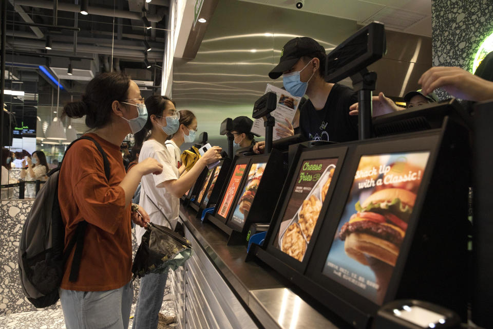 Workers attend to customers at the opening of the first Beijing outlet for Shake Shack in Beijing on Wednesday, Aug. 12, 2020. The U.S. headquartered burger chain is opening its first Beijing restaurant at a time when China and the U.S. are at loggerheads over a long list of issues. (AP Photo/Ng Han Guan)