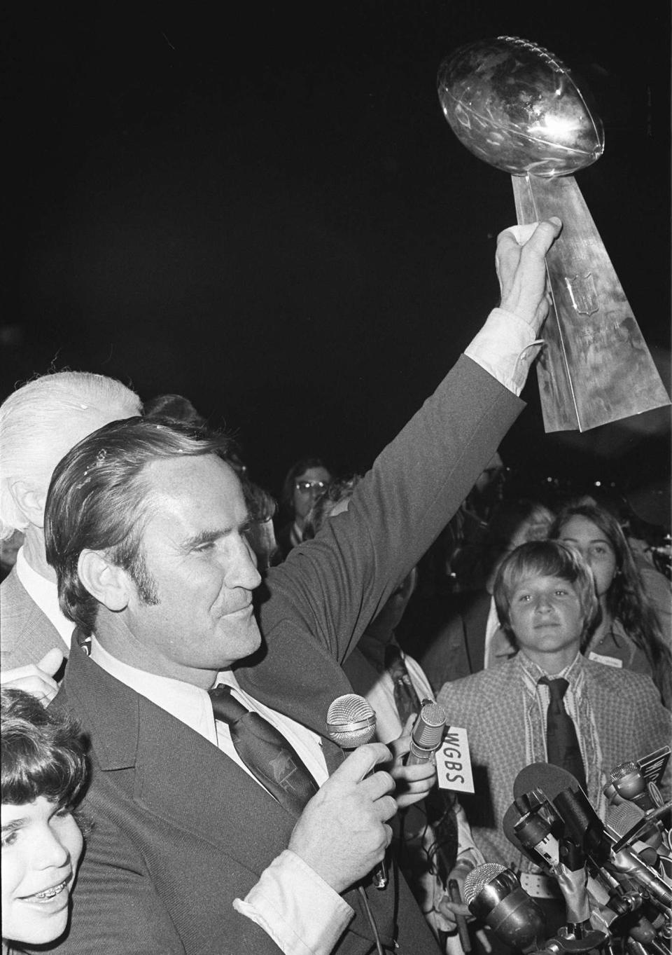 FILE- Miami Dolphins coach Don Shula waves the Vince Lombardi trophy, Jan. 15, 1973, as the team arrives in Miami after winning the Super Bowl. Shula's son David looks on at right. The Dolphins defeated the Washington Redskins in Super Bowl VII to become the first and still, the only team to have an undefeated season. (AP Photo/File)