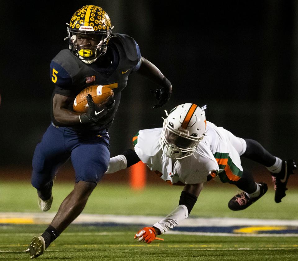 Naples Golden Eagles running back Shawn Simeon (5) runs upfield as Dunbar Tigers safety Garyan Burger (12) dives for him during the second quarter of the Class 3S regional championship at Staver Field in Naples on Friday, Nov. 24, 2023.