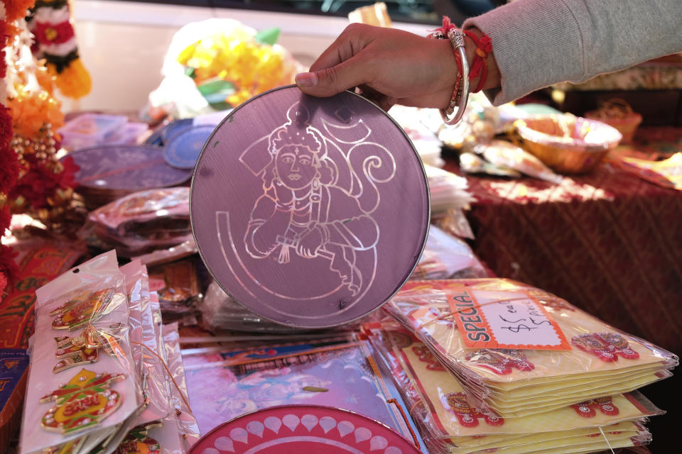 Pratik Shetty, the son of the proprietor of Flowers by Bhanu, shows off a stencil for rangoli -- colored powder designs -- on sale at a Diwali stall in the Jackson Heights neighborhood in the Queens borough of New York on Oct. 22, 2022. (AP Photo/Mallika Sen)