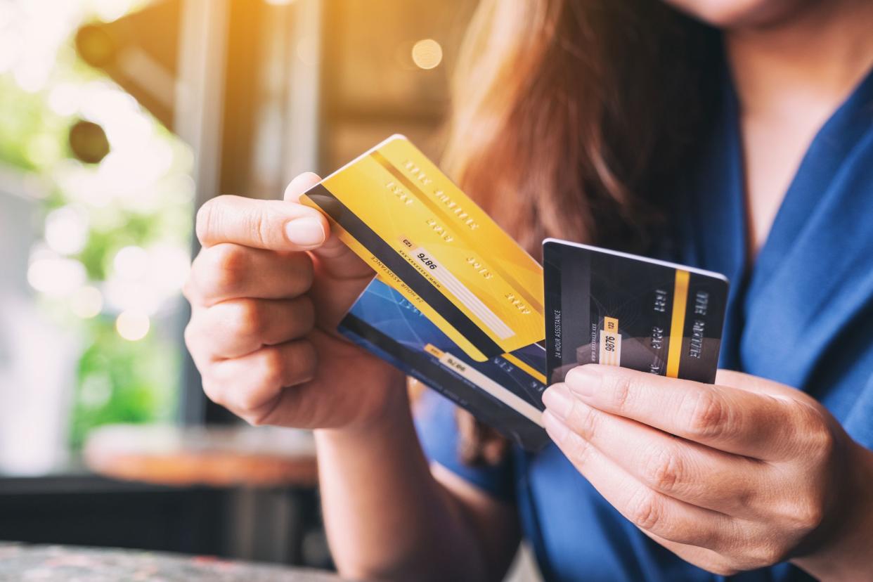 Closeup of a woman holding three credit cards and choosing which one to use, with restaurant in the background