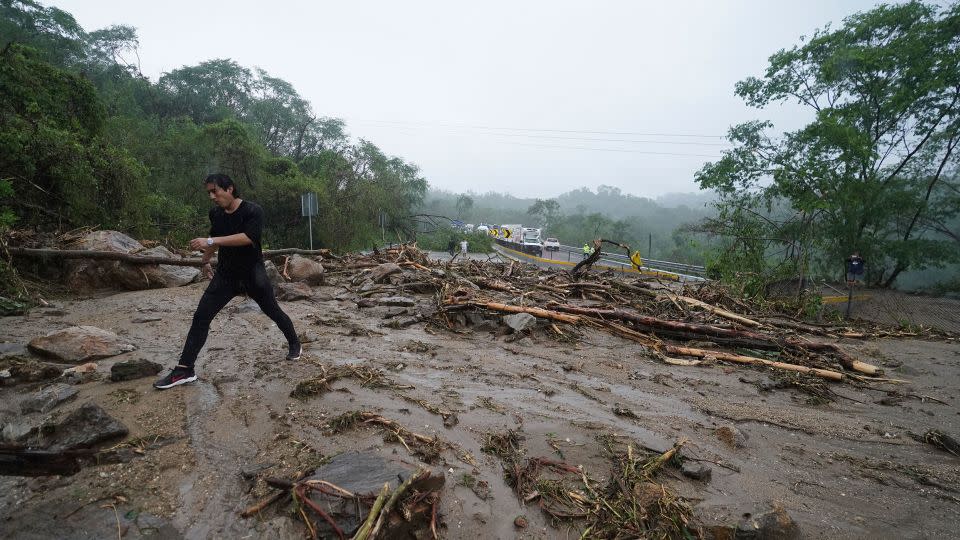 A man on Wednesday crosses a highway blocked by a landslide triggered by Hurricane Otis near Acapulco. - Marco Ugarte/AP