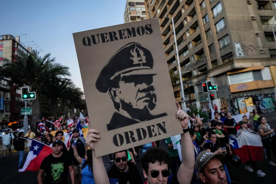 A man holds a sign of Chile's late Gen. Augusto Pinochet with the Spanish message: "We want order," at a protest on April 6, 2023 following the murder of police officer Daniel Palma, the third killing of an officer in the previous 23 days.