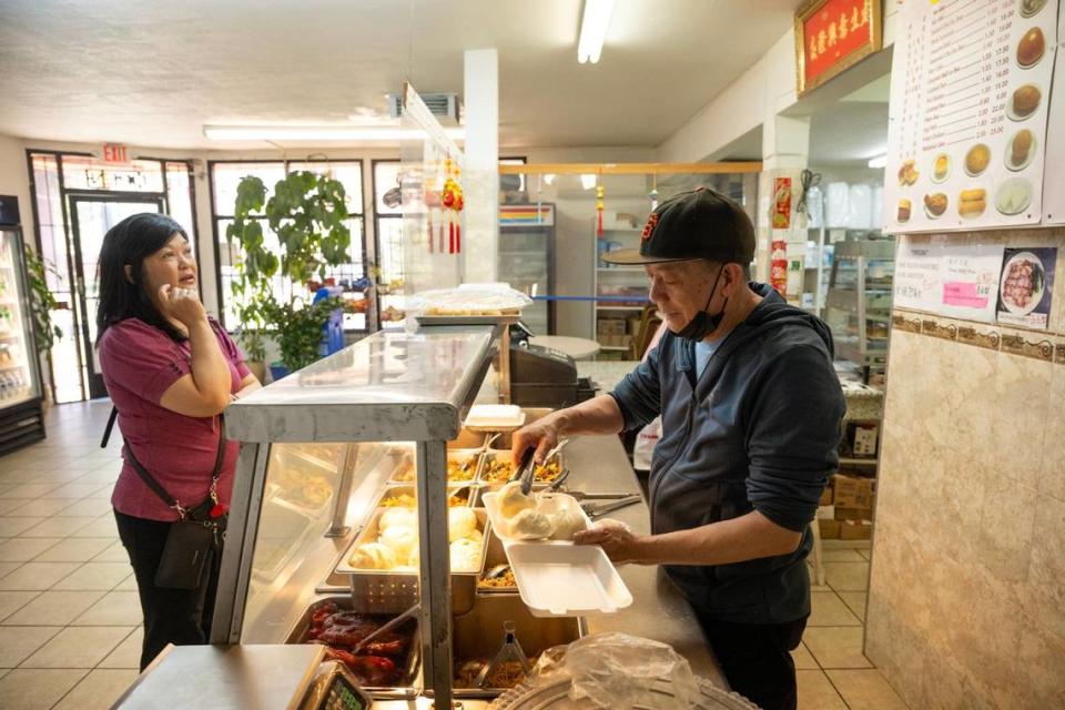 Owner Yao Li picks out a cha siu bao for a customer, Jo-Ann Lin, at Lam Kwong Deli & Market on Wednesday, March 20, 2024, in Sacramento.