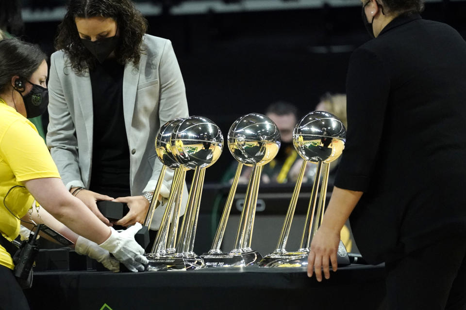 Workers reach to remove the four Seattle Storm championship trophies before a WNBA basketball game against the Las Vegas Aces Saturday, May 15, 2021, in Everett, Wash. The Storm won the 2020 championship. (AP Photo/Elaine Thompson)