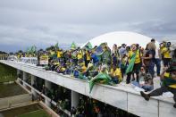 FILE - Protesters, supporters of Brazil's former President Jair Bolsonaro, stand on the roof of the National Congress building after they stormed it, in Brasilia, Brazil, Jan. 8, 2023. An investigation into anti-democratic protests and a recent attack on Brazil's capital is centering in part on areas along an important highway that goes through the Amazon. (AP Photo/Eraldo Peres, File)