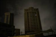 In this May 23, 2019 photo, only two apartments of a building are illuminated by electric generators during a black out in Maracaibo, Venezuela. Some have opted for small generation units costing a few hundred dollars that can pump out enough power to run a few appliances at a time, such as using the lights and water heater for a shower. (AP Photo/Rodrigo Abd)