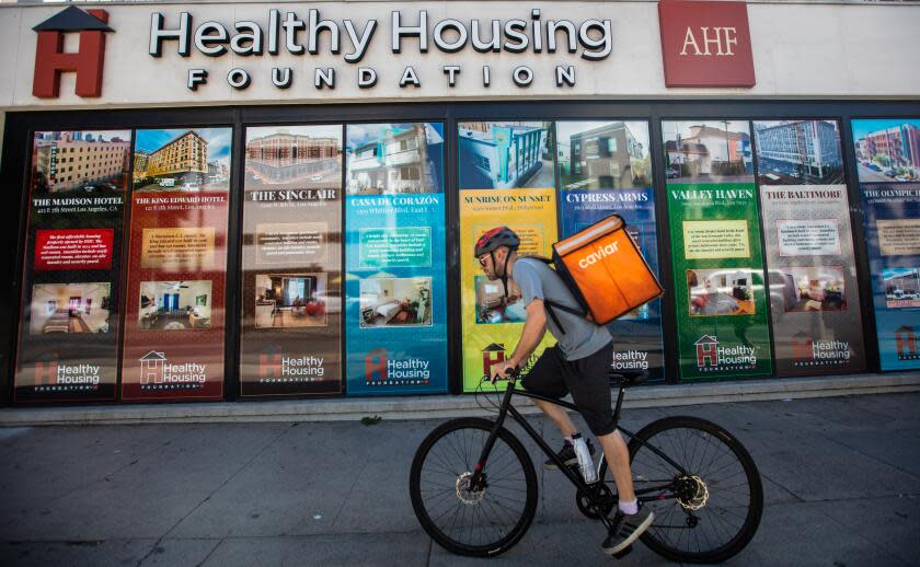 Los Angeles, CA - September 07: (**NOTE: This image is to be used for a specific story by Liam Dillon.) A cyclist rides past the Healthy Housing Foundation AHF located on Sunset Blvd. in Hollywood on Thursday, Sept. 7, 2023, in Los Angeles, CA. (Francine Orr / Los Angeles Times)