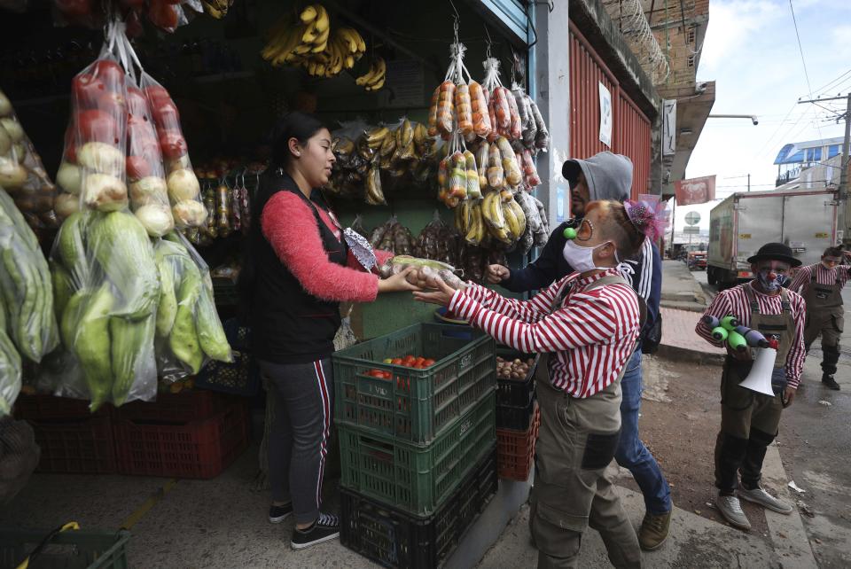 Alexandra "Calabacita" Suárez, miembro de la compañía del grupo "Circo Encuentro", recibe vegetales donados con los que prepararán una gran sopa para personas de bajos recursos afectados por la pandemia del nuevo coronavirus, en Bogotá, Colombia, el sábado 4 de julio de 2020. (Foto AP/Fernando Vergara)