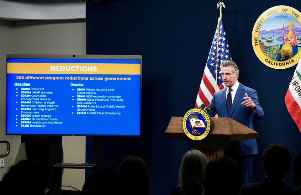 A slide shows some of the proposed reductions in Gov. Gavin Newsom’s revised $288 billion budget proposal on Friday.