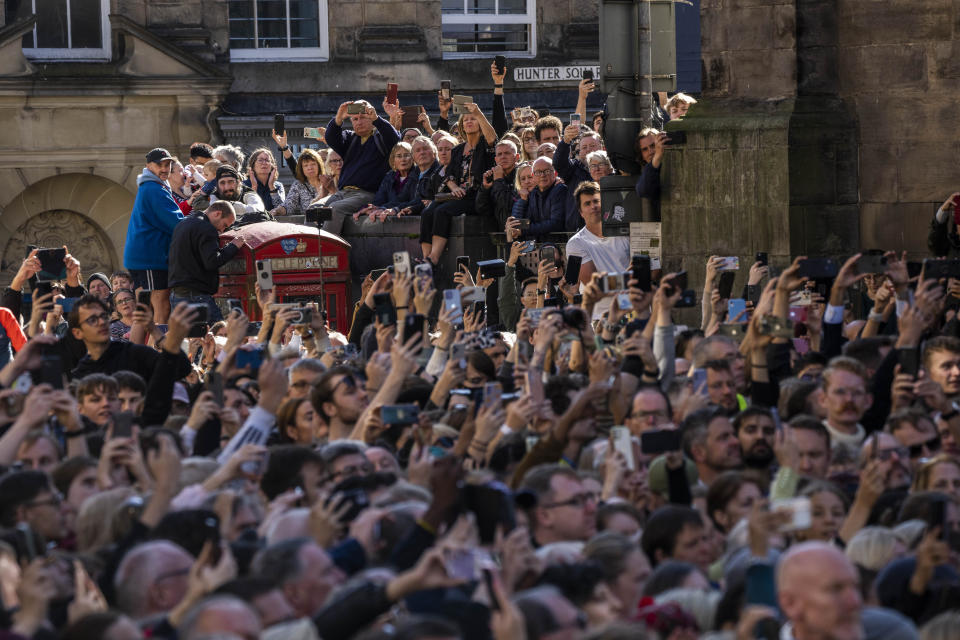 People attend the procession of Queen Elizabeth II's coffin, from the Palace of Holyroodhouse to St Giles Cathedral, on the Royal Mile in Edinburgh, Scotland, Monday Sept. 12, 2022. Britain's longest-reigning monarch who was a rock of stability across much of a turbulent century, died Thursday Sept. 8, 2022, after 70 years on the throne. She was 96. (AP Photo/Bernat Armangue)