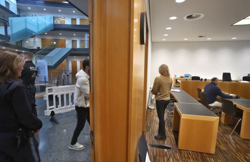 The 19-year-old defendant (L) enters a courtroom in the criminal justice center. A German court sentenced a man to a juvenile prison term on Wednesday in connection with the tearing down of an Israel flag hung in front of Augsburg City Hall in Bavaria. Karl-Josef Hildenbrand/dpa