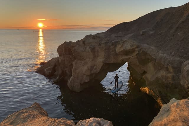 A paddleboarder watches the sun rise at Cullercoats bay in North Tyneside on August 8 