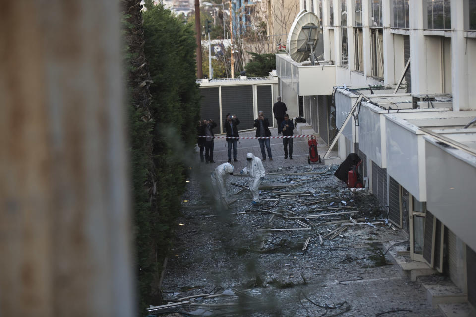 Greek forensic experts search the debris after a powerful bomb exploded outside private Greek television station Skai, in Faliro, Athens, on Monday, Dec, 17, 2018. Police said the blast occurred outside the broadcasters' headquarters near Athens after telephoned warnings prompted authorities to evacuate the building, causing extensive damage but no injuries. (AP Photo/Petros Giannakouris)