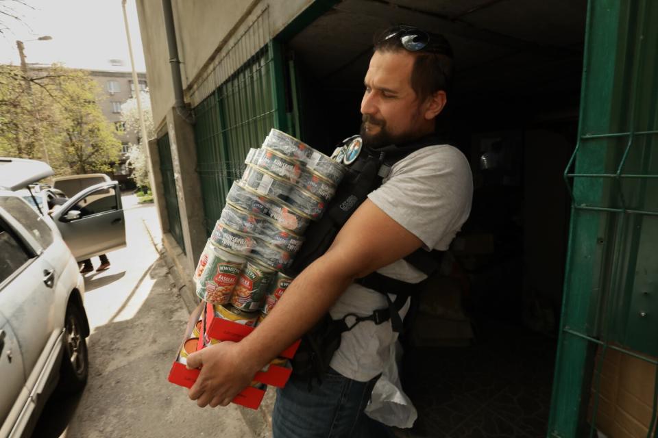 Volunteer holds a tower of canned food and medicine