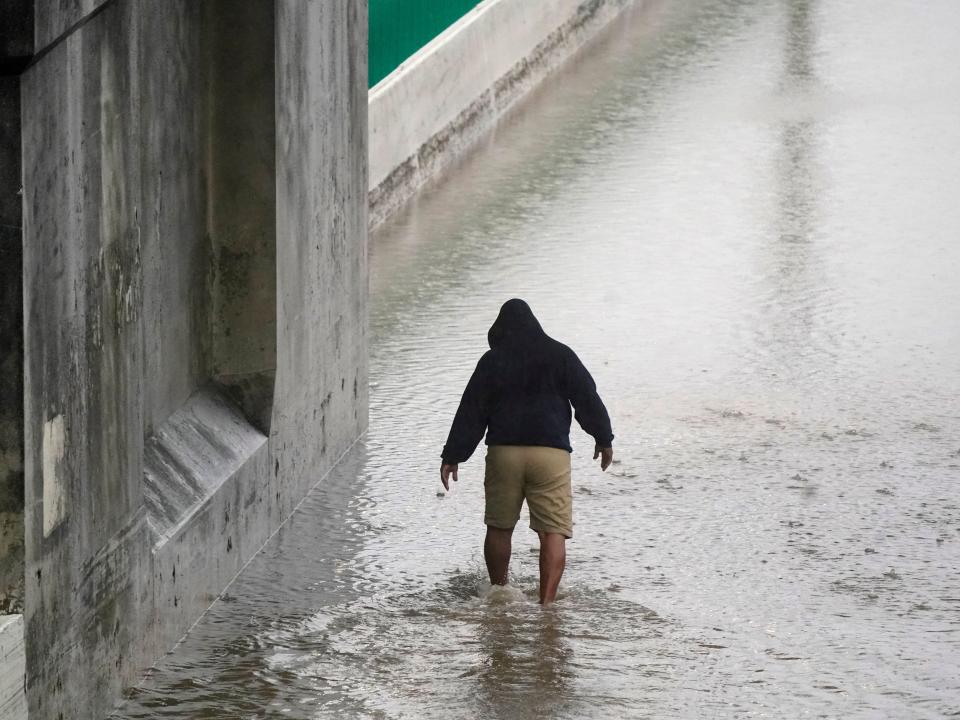 Semi-truck driver Steven Virgil walks into flood waters covering a closed highway to check the depth before trying to drive his truck through in Dallas, Monday, Aug. 22, 2022.