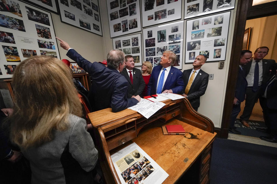 Republican presidential candidate former President Donald Trump looks a a photo of himself filing for 2016 with New Hampshire Secretary of State David Scanlan as he signs papers to be on the 2024 Republican presidential primary ballot at the New Hampshire Statehouse, Monday, Oct. 23, 2023, in Concord, N.H. At right is Corey Lewandowski. (AP Photo/Charles Krupa)