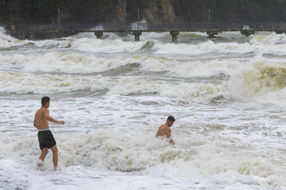 Swimmers take to the sea as the top part of New Zealand is hit by a cyclone, in Auckland, New Zealand, Sunday, Feb. 12, 2023. New Zealand's national carrier has canceled dozens of flights as Aucklanders brace for a deluge from Cyclone Gabrielle, two weeks after a record-breaking storm swamped the nation's largest city and killed four people. (Brett Phibbs/NZ Herald via AP)