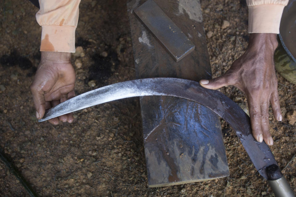 An Indonesian migrant worker sharpens the blade of his sickle used for cutting down palm oil fruit from tall trees in Sabah, Malaysia, on Monday, Dec. 10, 2018. Many Indonesians working in Malaysia do not have proper documents, leaving them vulnerable to exploitation, arrest or deportation. (AP Photo/Binsar Bakkara)