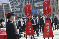 People wearing face masks pass members of the Salvation Army's campaign for the donation of face masks and money to impoverished people amid the spread of the new coronavirus in Seoul, South Korea, Wednesday, March 25, 2020. For most people, the new coronavirus causes only mild or moderate symptoms, such as fever and cough. For some, especially older adults and people with existing health problems, it can cause more severe illness, including pneumonia. The sign reads: "The Salvation Army and charity pot." (AP Photo/Ahn Young-joon)