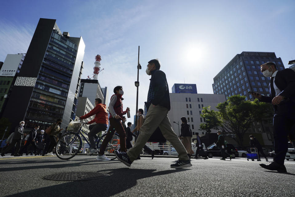 People wearing protective masks to help curb the spread of the coronavirus walk a street in Tokyo on April 15, 2021. The picture is still grim in parts of Europe and Asia as variants of the virus fuel an increase in new cases and the worldwide death toll closes in on 3 million. (AP Photo/Eugene Hoshiko)