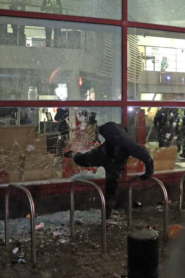 A protester kicks a smashed Bridewell police station window in Bristol 