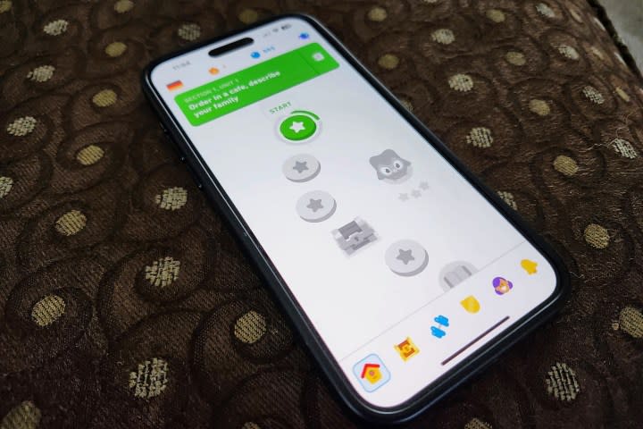 An iPhone 15 Pro Max showing the Duolingo app sitting on an ottomen.