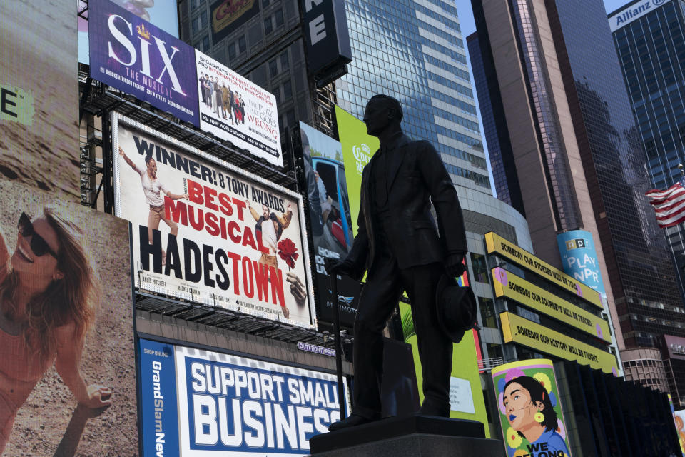 Una estatua del dramaturgo y actor George M. Cohan en Times Square, frente a carteles de distintos musicales de Broadway, el jueves 6 de mayo de 2021 en Nueva York. El gobernador Andrew Cuomo anunció que los teatros de Broadway podrán reabrir el 14 de septiembre de 2021. (AP Foto/Mark Lennihan)