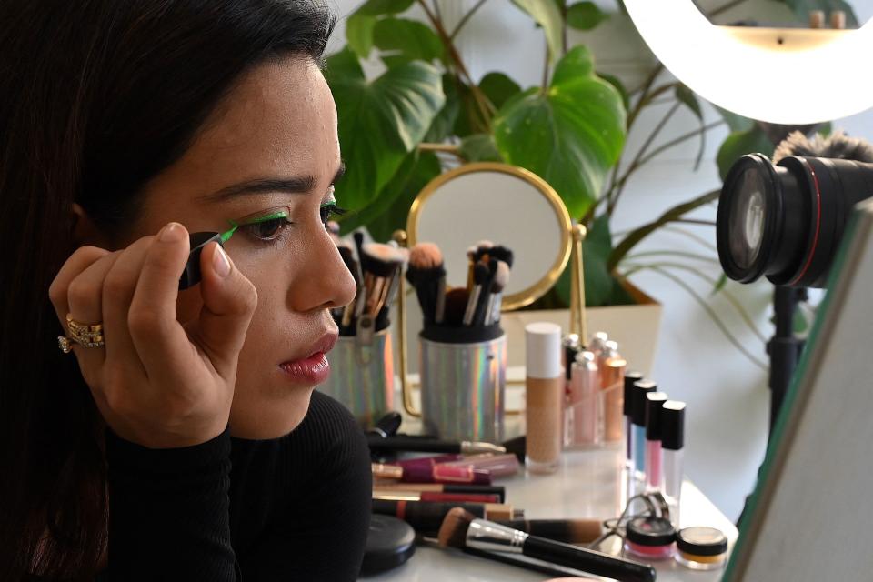 In this photo taken on March 16, 2023, social media beauty and lifestyle influencer Debasree Banerjee puts on makeup during a livestream on her YouTube channel in Mumbai.  - In the glow of a ring in a guest room in a Mumbai skyscraper, Indian makeup artist Debasree Banerjee has found fans around the world with a simple mantra: bronze is beautiful.  (Photo by SUJIT JAISWAL / AFP) / To AFP article 