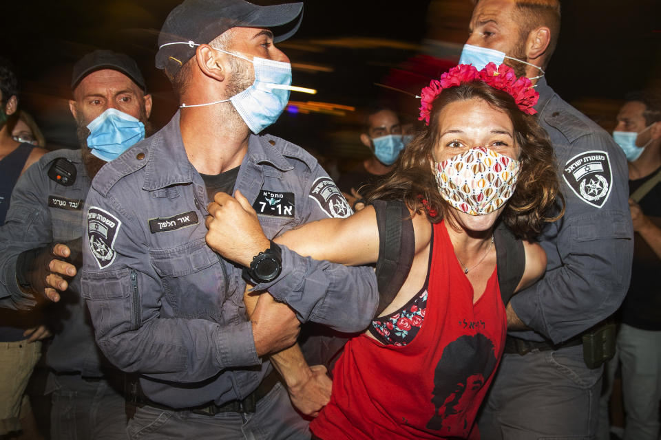 Israeli police officers arrest a demonstrator during a protest against Israel's Prime Minister Benjamin Netanyahu outside his residence in Jerusalem Sunday, July 26, 2020. Protesters demanded that the embattled Israeli leader resign as he faces a trial on corruption charges and grapples with a deepening coronavirus crisis. (AP Photo/Ariel Schalit)