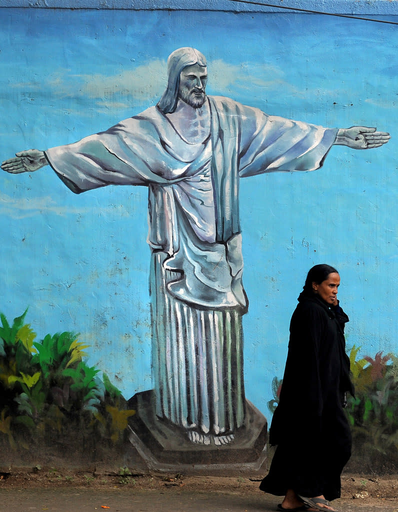 An Indian woman walks past a wall mural depicting Jesus Christ in Bangalore.<br>AFP PHOTO/Dibyangshu Sarkar.