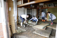 Residents clean a house damaged by Typhoon Hagibis, in Marumori town, Miyagi prefecture, Japan Monday, Oct. 14, 2019. Rescue crews in Japan dug through mudslides and searched near swollen rivers Monday as they looked for those missing from the typhoon that caused serious damage in central and northern Japan. (Kyodo News via AP)