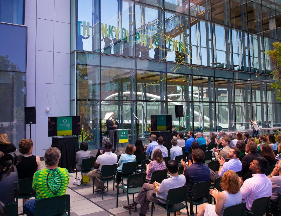 Confetti flies through the air inside the first Knight Campus  building and students hold up a "thank you" sign to Phil and Penny Knight as Robert E. Guldberg, executive director of the Knight Campus, center, announces the second $500 million gift from the Knights for the next phase of the science complex.