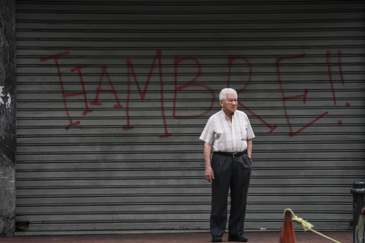 CARACAS, MIRANDA, VENEZUELA - 2018/08/21: An elderly man seen standing next to a graffiti saying Hunger in the streets of Caracas. The opposition called for a general strike for one day as a protest against the new currency and the economic measures applied by Maduros Government. (Photo by Roman Camacho/SOPA Images/LightRocket via Getty Images)