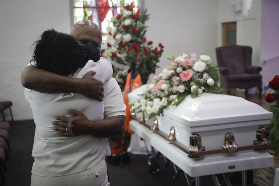 FILE - In this July 21, 2020, file photo, Darryl Hutchinson, facing camera, is hugged by a relative during a funeral service for Lydia Nunez, who was Hutchinson's cousin at the Metropolitan Baptist Church in Los Angeles. Nunez died from COVID-19. Southern California funeral homes are turning away bereaved families because they're running out of space for the bodies piling up during an unrelenting coronavirus surge. (AP Photo/Marcio Jose Sanchez, File)