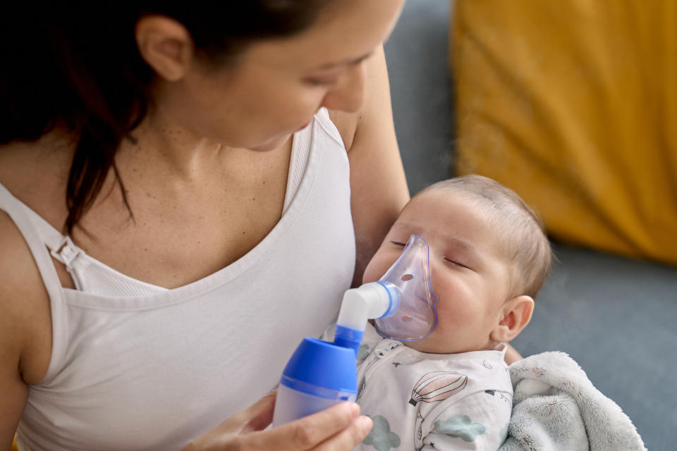 Frau lässt Baby mit einer Maske inhalieren