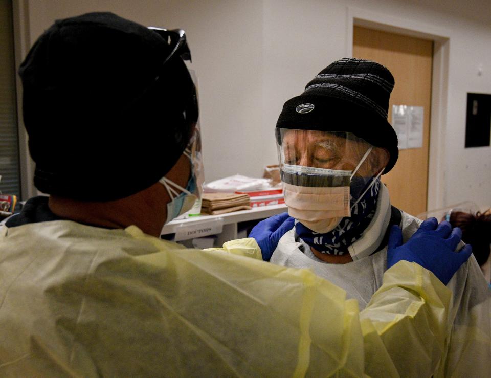 Lorenzo Dominguez Jr., left, preps his father, Lorenzo Dominguez Sr., before visiting their matriarch, Etelvina Dominguez, 78, on Friday, Feb. 12, 2021, at Providence Holy Cross Medical Center in Los Angeles. Due to COVID-19 protocols, the two were the only ones briefly allowed inside of the hospital to visit Etelvina.