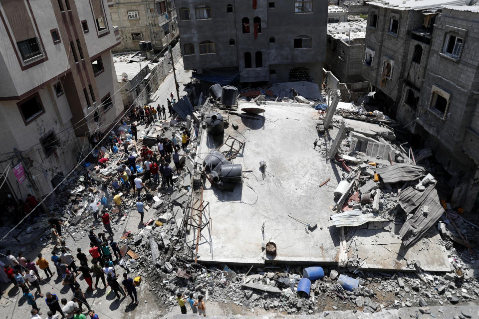People gather near the rubble of destroyed residential building which was hit by Israeli airstrikes, in Beit Lahiya, Gaza Strip, Thursday, May 20, 2021. (AP Photo/Adel Hana)
