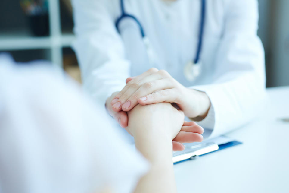 Friendly female doctor's hands holding female patient's hand for encouragement and empathy. Partnership trust and medical ethics concept.