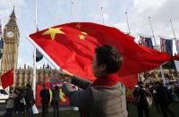 A supporter of China's President Xi Jinping waves a Chinese flag opposite Big Ben in Parliament Square ahead of Xi's address to both Houses of Parliament, in London, Britain, October 20, 2015. REUTERS/Peter Nicholls