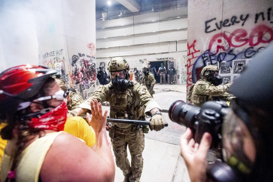 A federal officer pushes back demonstrators at the Mark O. Hatfield United States Courthouse on Tuesday, July 21, 2020, in Portland, Ore. A federal judge is hearing arguments on Oregon's request for a restraining order against federal agents who have been sent to the state's largest city to quell protests that have spiraled into nightly clashes between authorities and demonstrators.(AP Photo/Noah Berger)